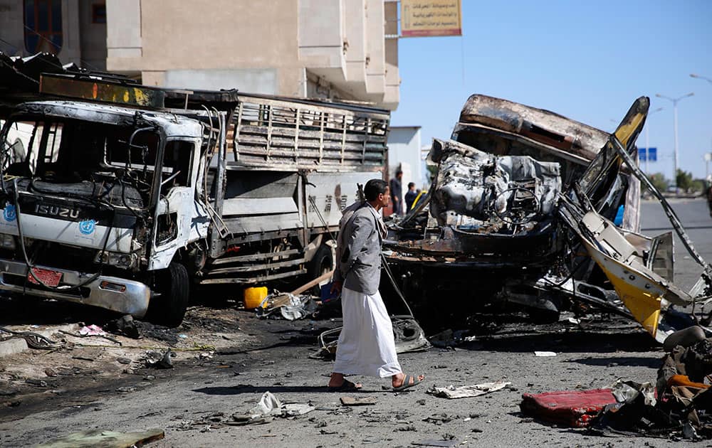 A man stand next to the wreckage of a truck at the site of a bomb attack in Sanaa, Yemen.