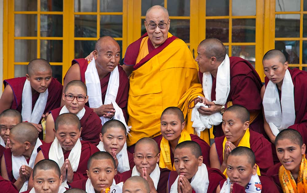Tibetan spiritual leader the Dalai Lama, in yellow robe, poses for a photograph with a group of monks and nuns wearing ceremonial scarves at the Tsuglakhang temple in Dharmsala.