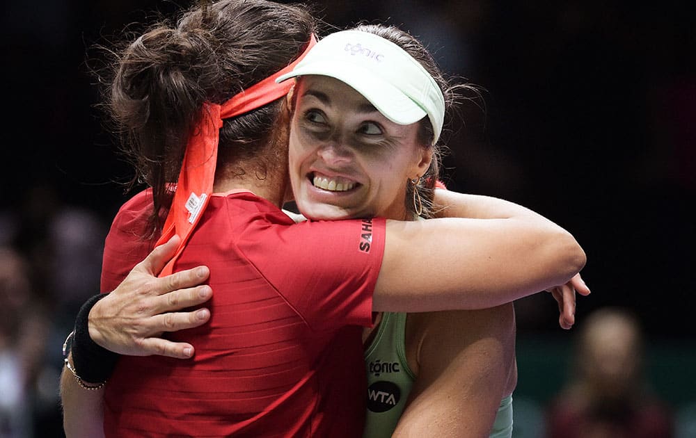 Sania Mirza of India, left, and Martina Hingis of Switzerland, right, embrace after they beat Carla Suarez Navarro and Garbine Muguruza, both of Spain during the doubles final at the WTA tennis finals in Singapore. 