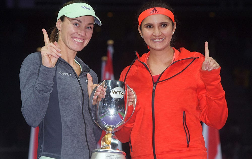 Martina Hingis of Switzerland, left, and Sania Mirza of India, right, pose with their trophy after they beat Carla Suarez Navarro and Garbine Muguruza, both of Spain during the doubles final at the WTA tennis finals in Singapore.