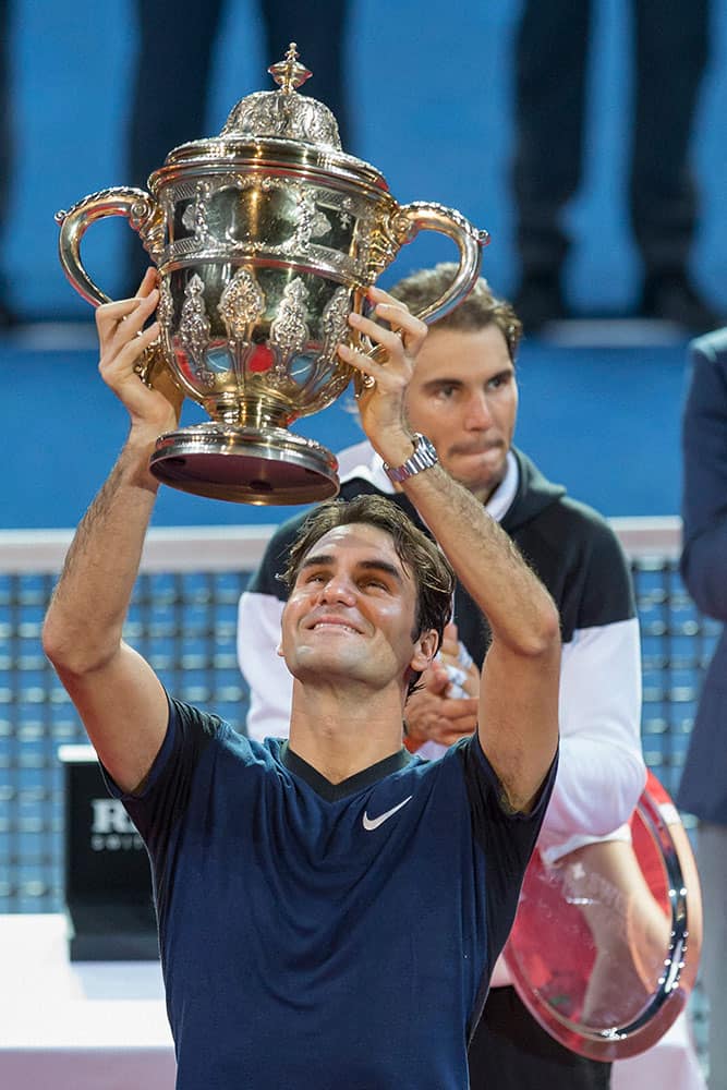 Switzerlands Roger Federer, front, smiles after winning his final match against Spains Rafael Nadal, back, at the Swiss Indoors tennis tournament at the St. Jakobshalle in Basel, Switzerland.