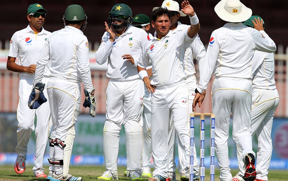 Pakistan’s bowler Yasir Shah celebrates dismissal of England's Alastair Cook with his team mates during Pakistan and England Test match at the Sharjah Cricket Stadium in Sharjah, United Arab Emirates.