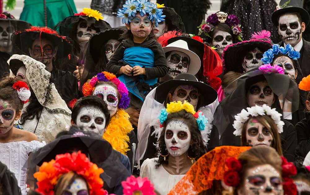 A girl in costume is held up during a Catrina Fest to commemorate Day of the Dead, a holiday that honors the deceased, in Mexico City.