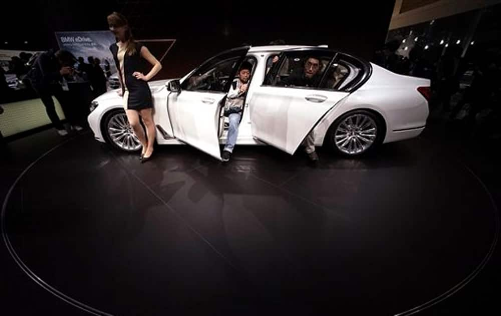 Guests try to get in a BMW 740Li displayed during the media preview of the Tokyo Motor Show in Tokyo, Wednesday, Oct. 28, 2015.
