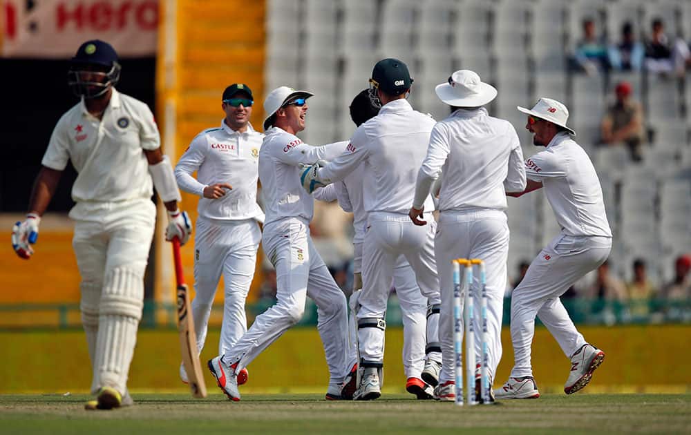 South African cricketers celebrate the dismissal of India's Cheteshwar Pujara during the first day of their first cricket test match in Mohali.