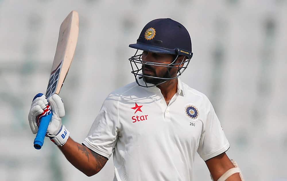 India's Murali Vijay raises his bats after scoring half a century during the first day of their first cricket test match against South Africa in Mohali.