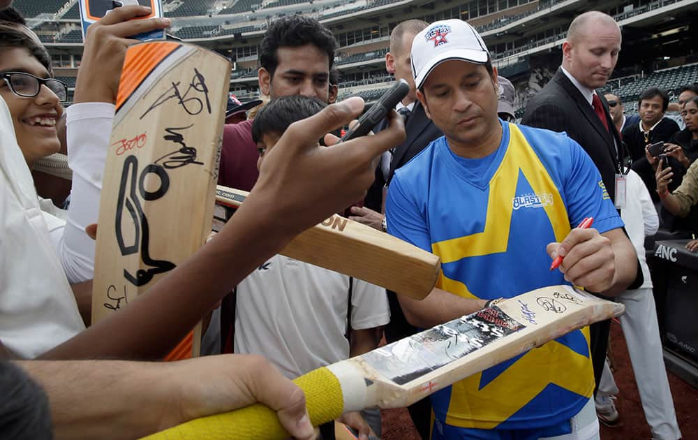 Retired cricketer Sachin Tendulkar autographs cricket bats during a clinic for kids ahead of the Cricket All-Stars series, at Citi Field in New York. The three-game series will be played in Major League Baseball stadiums in New York, Houston and Los Angeles.