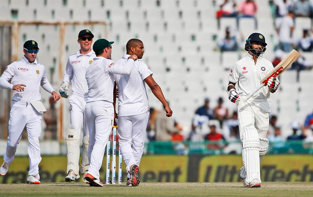 Shikhar Dhawan, walks back to the pavilion after being dismissed by South Africa's Vernon Philander, second right, during the second day of their first cricket test match in Mohali.