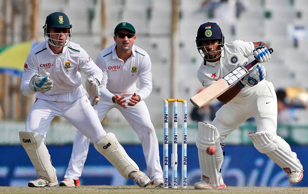 Wriddhiman Saha, right, bats with South African wicketkeeper Dane Vilas, left, and Dean Elgar fielding during the third day of their first cricket test match in Mohali.