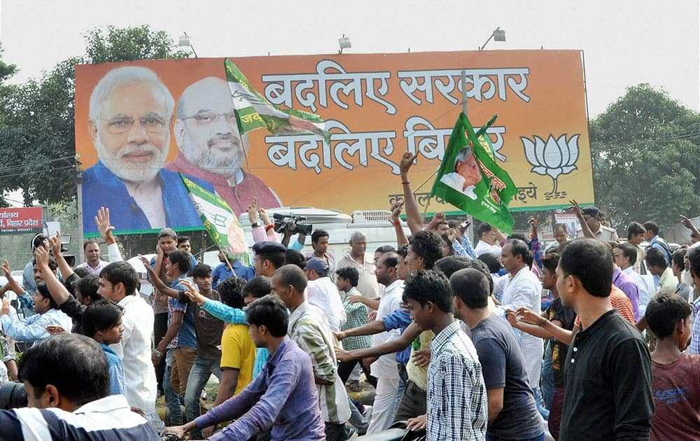 JD(U) supporters walk past a hoarding of BJP as they celebrate the Mahagathbandhans victory in Bihar assembly elections in Patna.