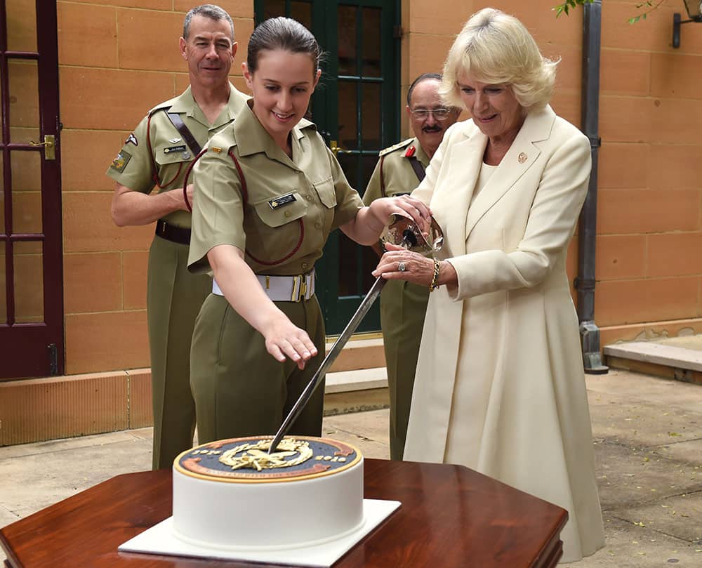 Britain's Camilla, Duchess of Cornwall, right, holds a sword as she prepares to cut a cake with Pvt. Alana Smilie, left, while visiting with the Royal Australian Corps of Military Police at the Victoria Barracks in Sydney.