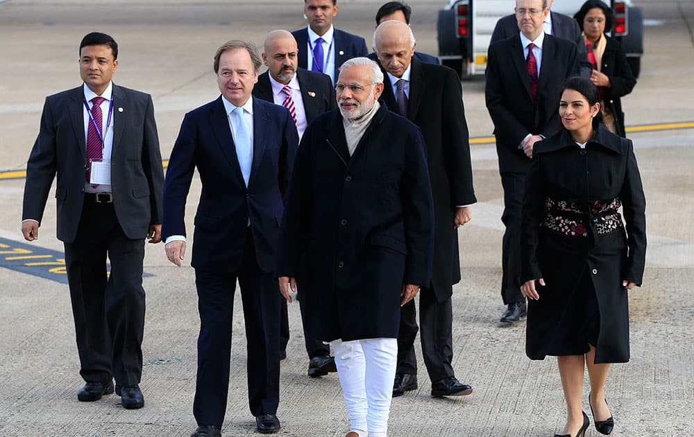 Indian Prime Minister Narendra Modi, center, is greeted by Minister of State for the Foreign and Commonwealth Office, Hugo Swire, left, and MP Priti Patel as he arrives at Heathrow Airport, London, for an official three day visit.