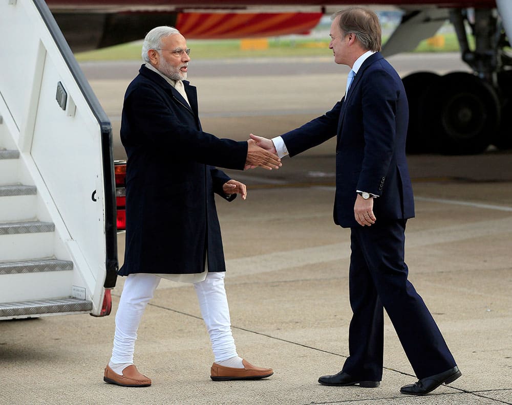 Indian Prime Minister Narendra Modi is greeted by Minister of State for the Foreign and Commonwealth Office, Hugo Swire, right, as he arrives at Heathrow Airport, London, for an official three day.