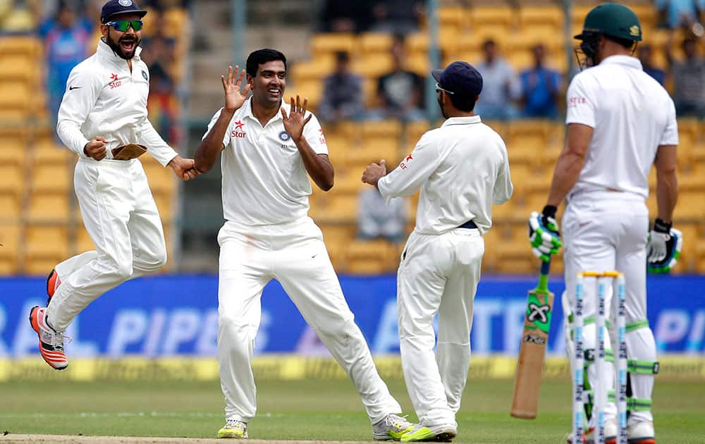 Ravichandran Ashwin and captain Virat Kohli celebrate the dismissal of South Africa's Faf du Plessis during the first day of their second cricket test match in Bangalore.