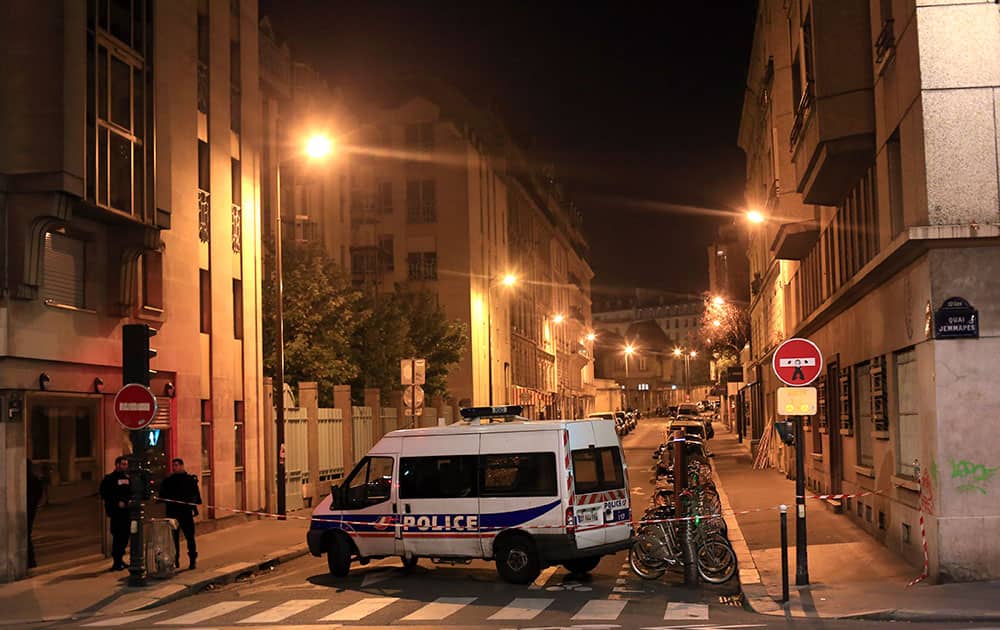 Police officers stand in a street next to Le Carillon, a bar-cafe where people were killed and several gravely injured, according to the prosecutor, in Paris.