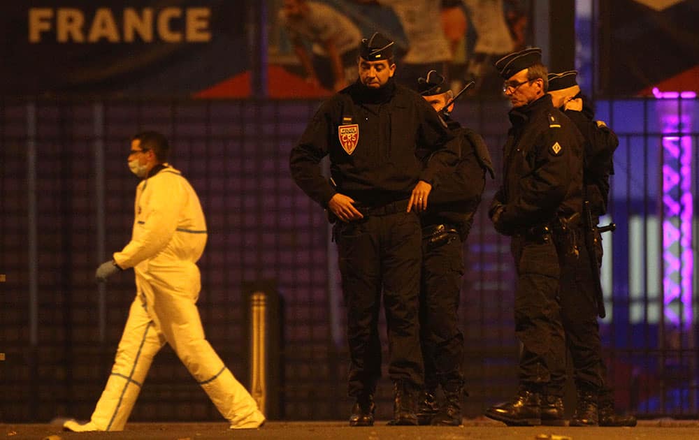 An investigating police officer, left, walks behing police officers outside the Stade de France stadium after an explosion and after international friendly soccer match France against Germany, in Saint Denis, outside Paris.