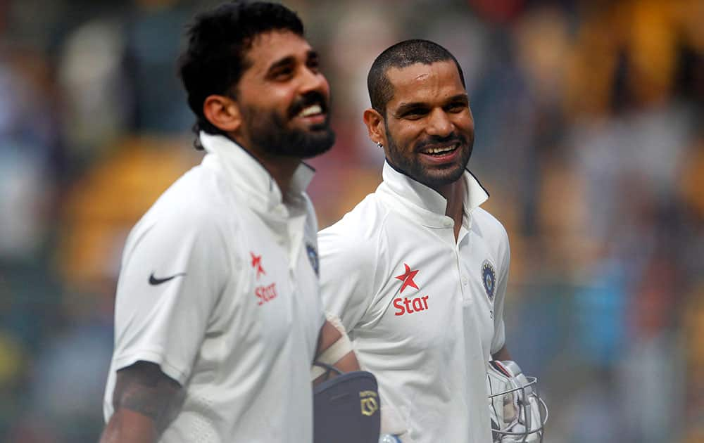 Murali Vijay and Shikhar Dhawan smile as they leave the ground at the end of the first day of their second cricket test match against South Africa in Bangalore.