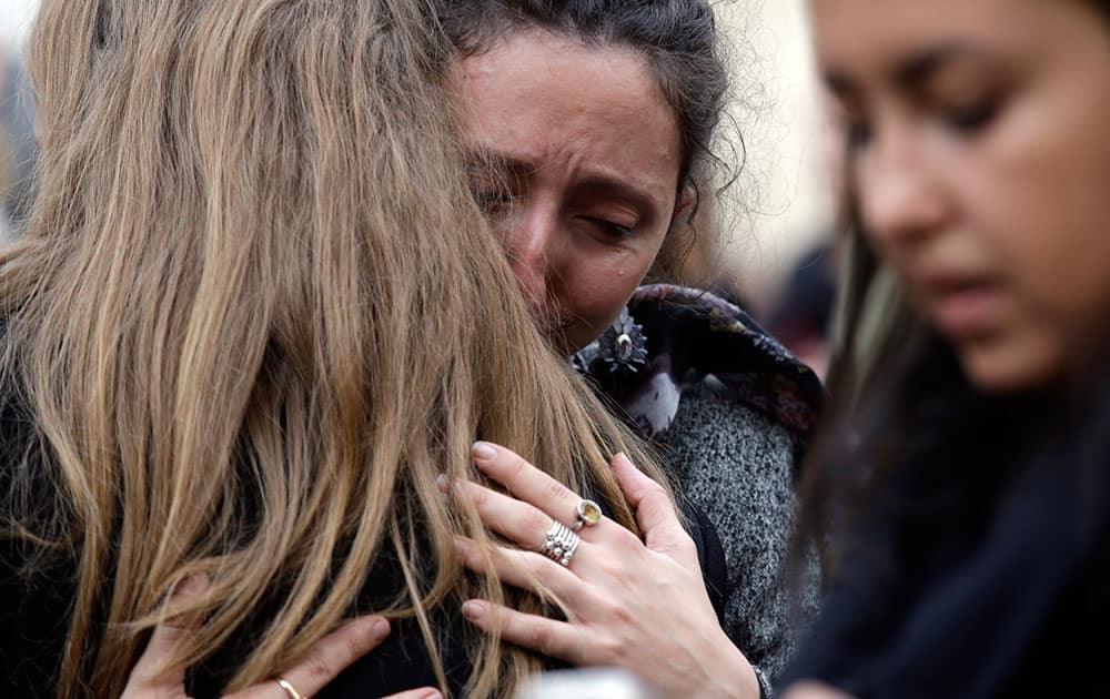 People hug each other as they gather in front of the French embassy in Rome.