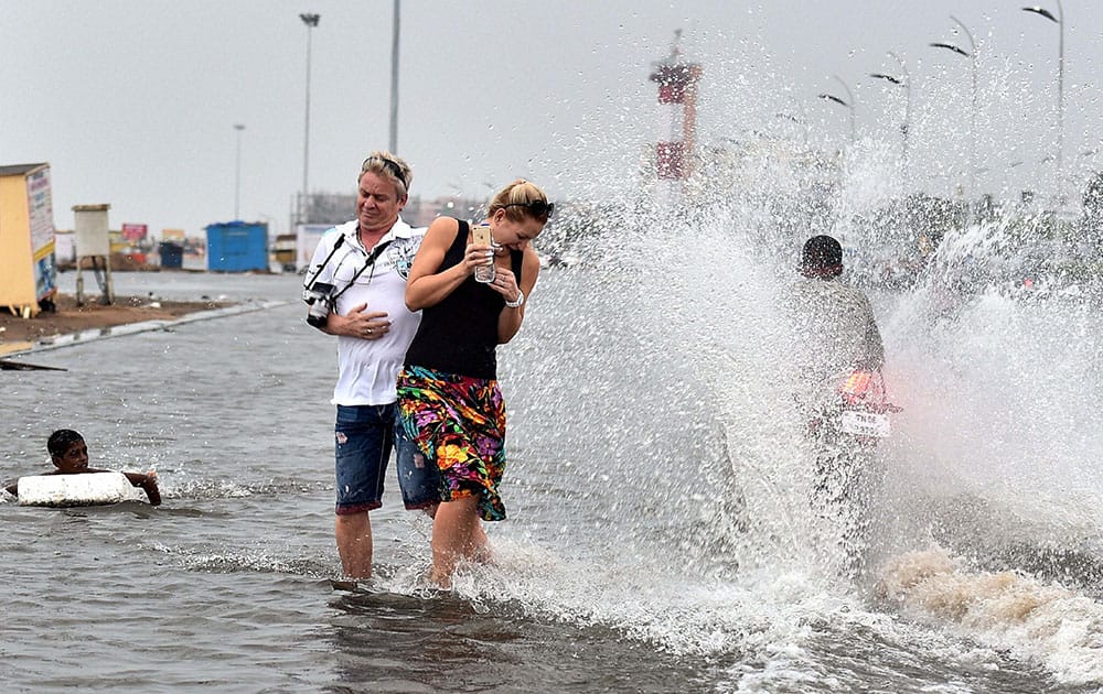 Foreigners trying to save themselves as a motorcycle splash water at Marina Beach in Chennai.
