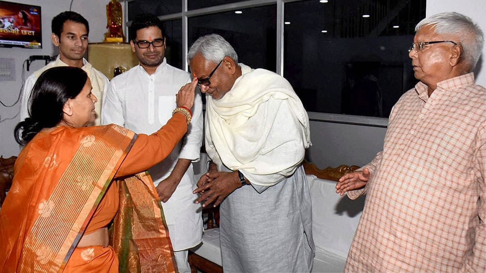 RJD leader Rabri Devi applying tikka to Bihar Chief Minister Nitish Kumar as RJD supremo Lalu Prasad looks on during Chhath festival in Patna.