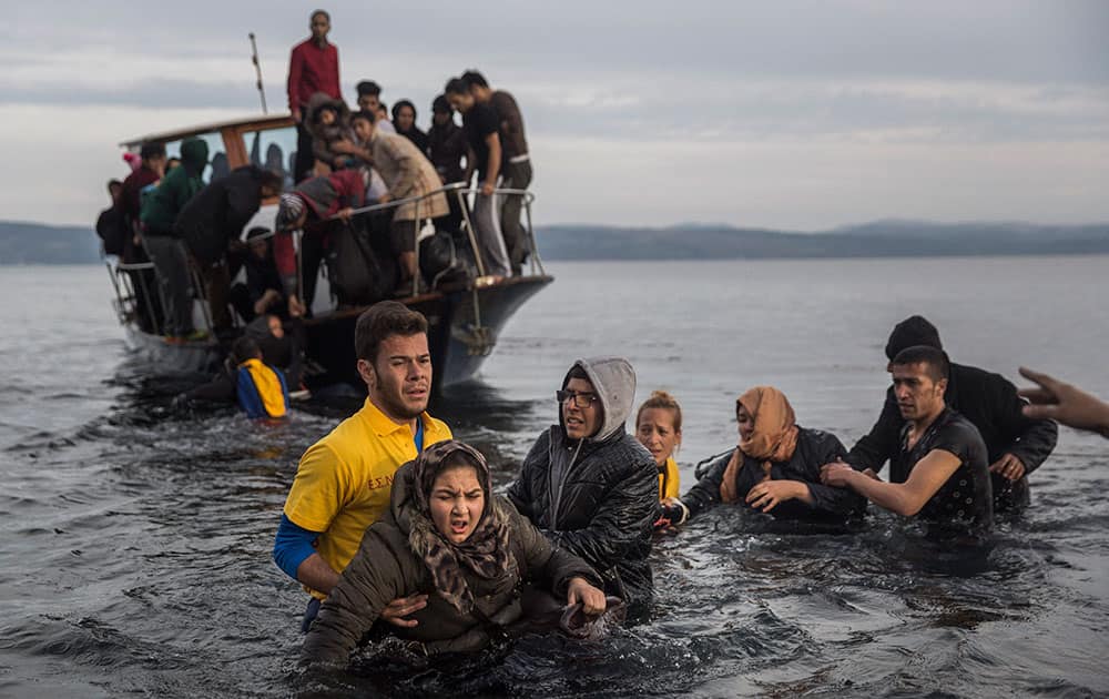 Greek lifeguards help refugees and migrants to disembark from a small boat after their arrival from the Turkish coast on the northeastern Greek island of Lesbos.