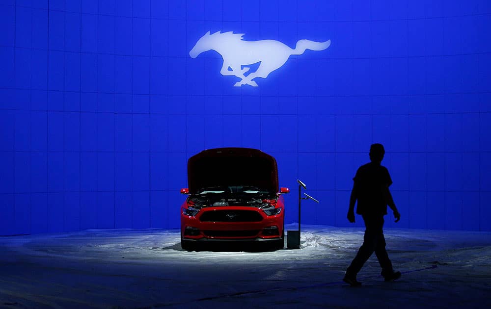 A worker walks past the 2016 Ford Mustang at the Los Angeles Auto Show in Los Angeles. 