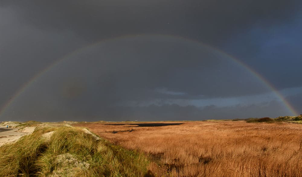 A rainbow stretches across the dunes at the North Sea in St.Peter-Ording, northern Germany. Storm front 'Iwan' brings strong winds and rain to northern Germany.