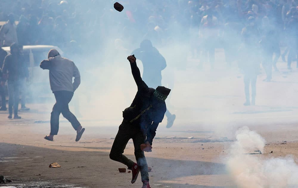 A Kashmiri protester throws stones as others run for cover from tear gas smoke fired by policemen during a protest in Srinagar.