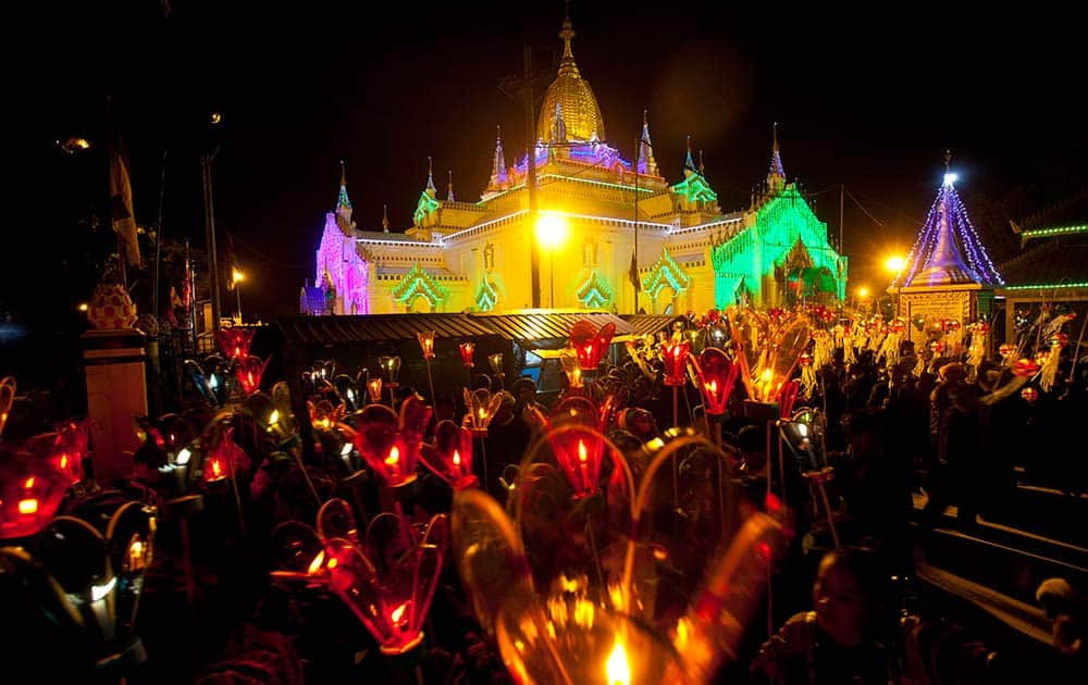 Ethnic Pa-O women march with paper lanterns during Tazaungdine Festival while Sulamani Pagoda is illuminated in Taunggyi, southern Shan State, Myanmar.