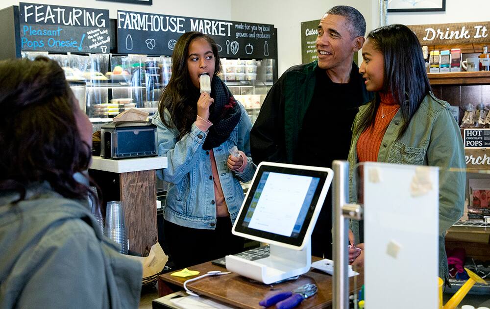 President Barack Obama, joined by his daughters Malia, left, and Sasha, right, orders at Pleasant Pops on Small Business Saturday in Washington.
