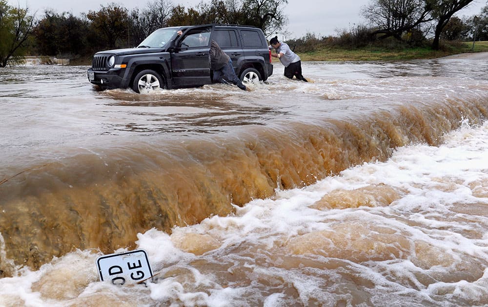 Two people push a vehicle out of high water at Cal Young Park in Abilene, Texas. 