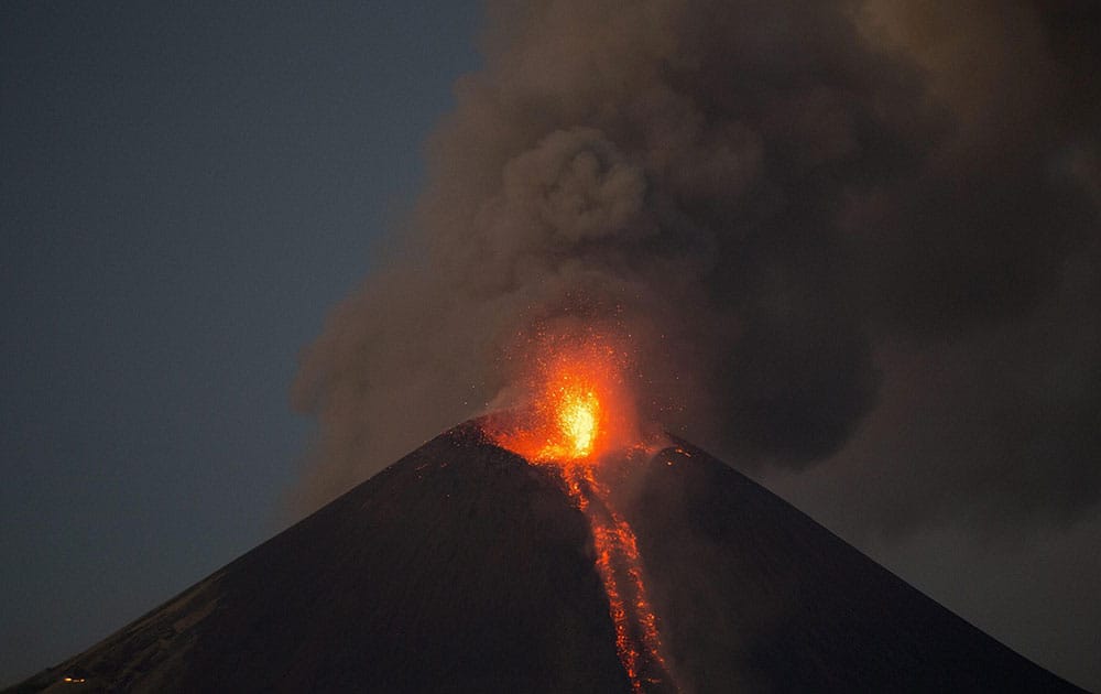 The Momotombo volcano spews a large plume of gas and ash as well as glowing rock, as seen from the rural community of Papalonal, in Leon, Nicaragua.