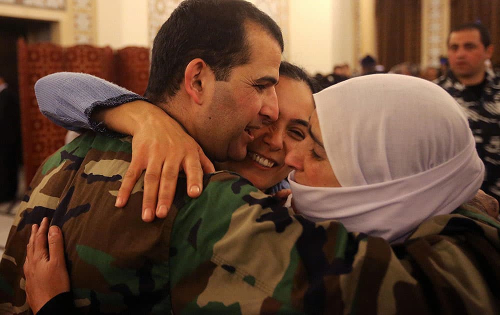 A Lebanese army soldier who was kidnapped by Nusra Front, left, is hugged by his mother and sister upon his arrival at the government palace, in Beirut, Lebanon.