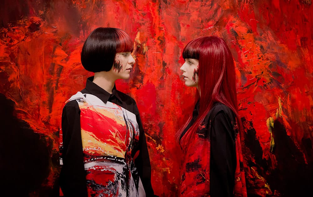 Models pose backdropped by a painting at the opening of an exhibition in Bucharest, Romania.