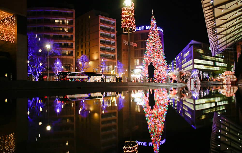 A man walks in front of the illuminated Christmas tree set up for the Christmas season at Potsdamer Platz in Berlin.