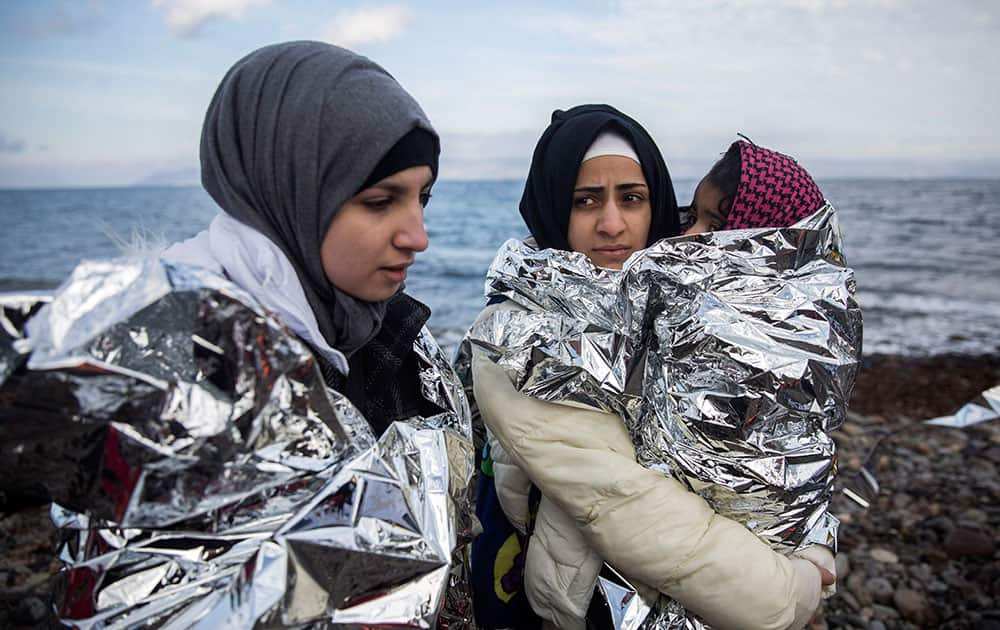 Women covered with thermal blankets after their arrival with other migrants and refugees on a dinghy from the Turkish coast to the northeastern Greek island of Lesbos.