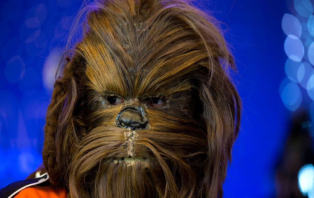 A Star Wars fan wearing a Chewbacca mask waits for the start of a fan event to promote 