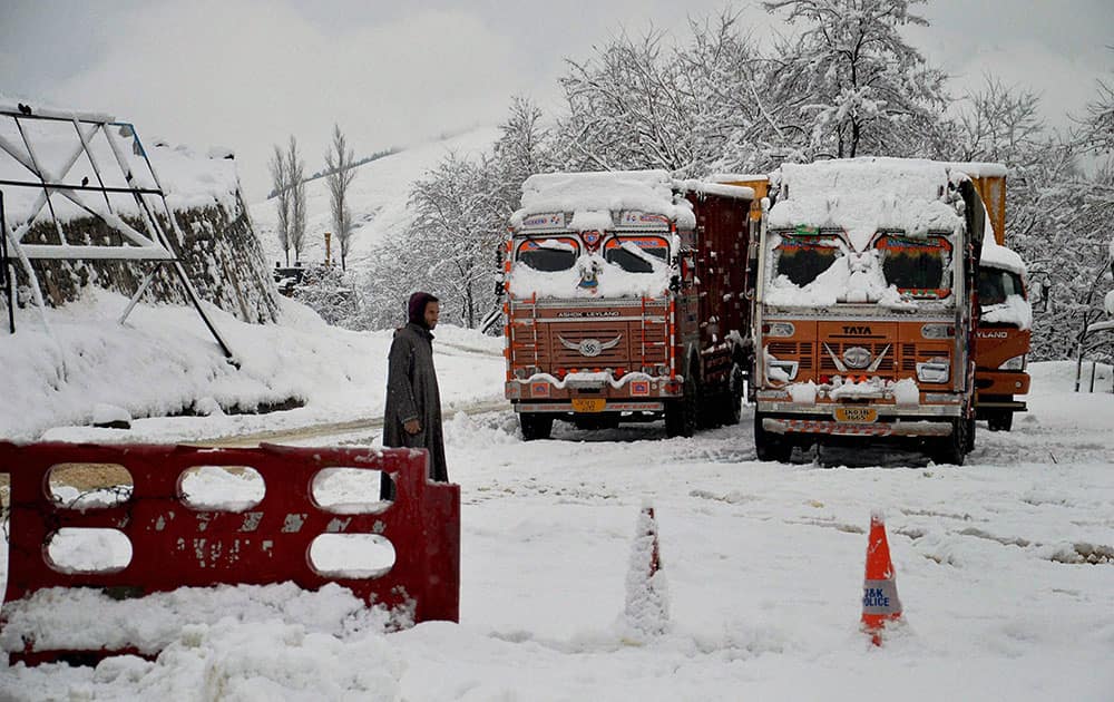A driver stands in front stranded trucks on snow-covered Srinagar-Jammu National Highway at Qazigund area of South Kashmir.