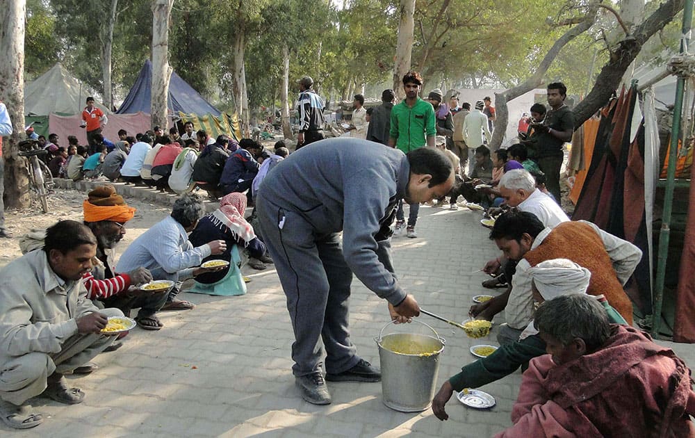 Residents whose houses were demolished in an eviction drive having food in Shakur Basti of Delhi.