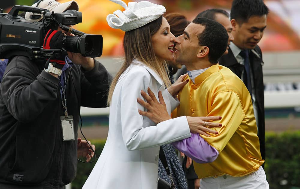 Brazilian jockey Joao Moreira kisses his wife as he celebrates after riding Hong Kong horse Peniaphobia to win the 1,200-meter Longines Hong Kong Sprint at Shatin race track in Hong Kong.