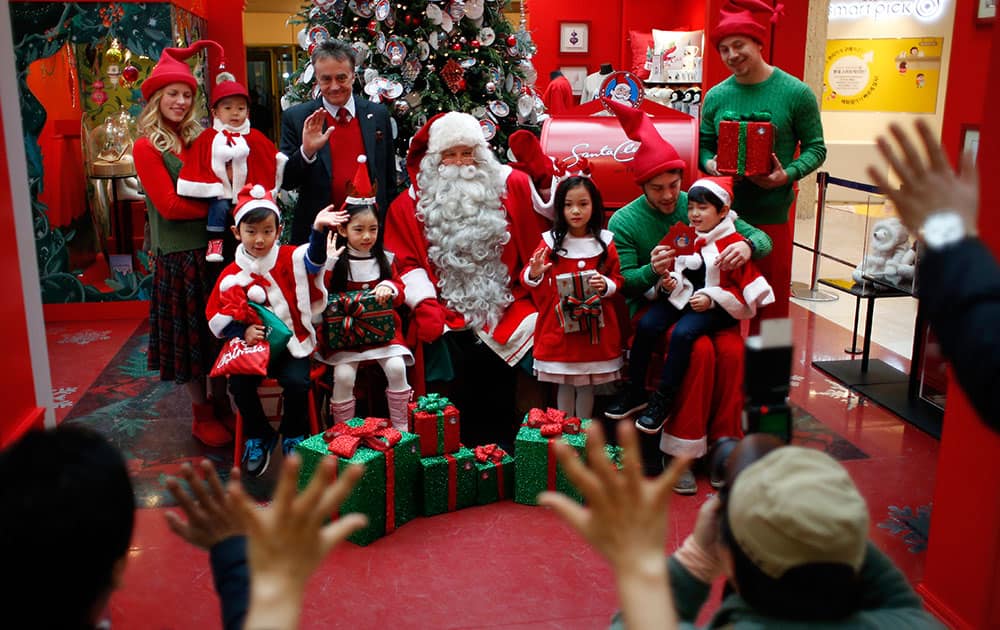 A man from Lapland, Finland, center, dressed as Santa Claus poses with children for photographers as part of a department store's Christmas celebration event in downtown Seoul, South Korea.