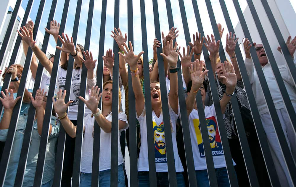 Lilian Tintori, the wife of jailed Venezuelan opposition leader Leopoldo Lopez, center, with the relatives of other political prisoners, yell “liberty” from inside a mock prison cell in Caracas, Venezuela.