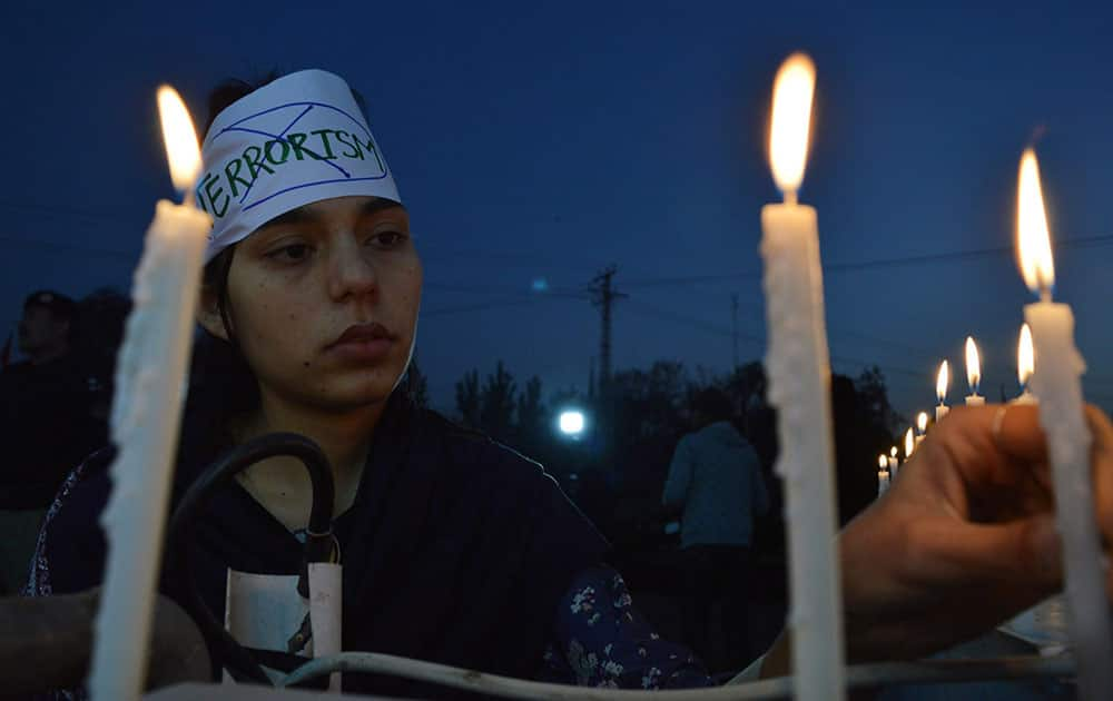 A member of Pakistans civil society holds a candlelit vigil in memory of students martyred in a deadly terrorists attack on an army public school last year.