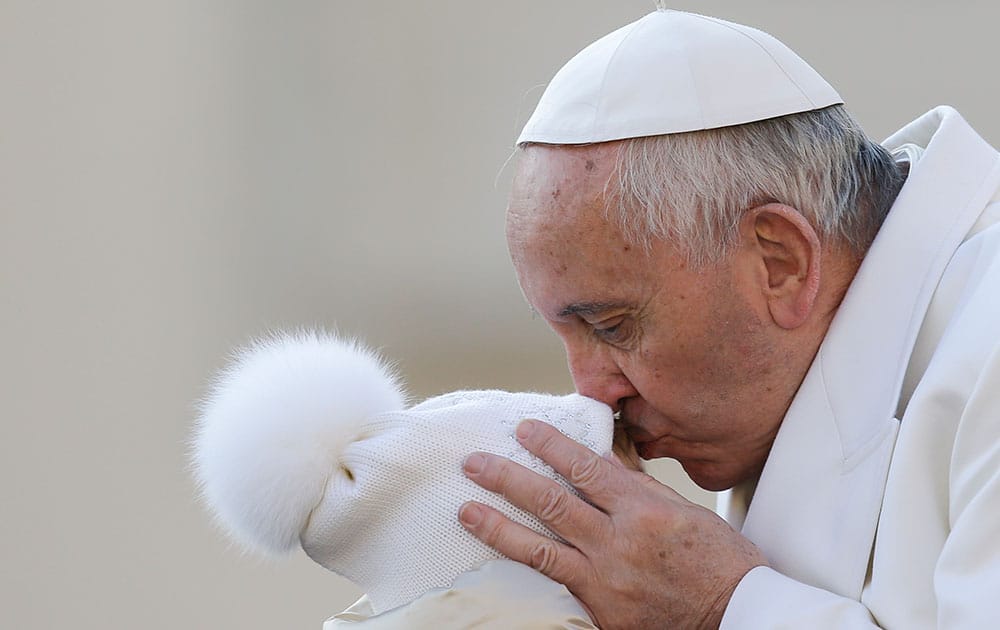 Pope Francis kisses a child upon his arrival for the weekly general audience at the Vatican.