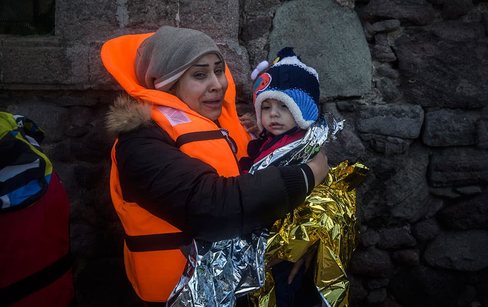 A woman holds a baby after their arrival with other refugees and migrants on a dinghy, from the Turkish coast to the Greek island of Lesbos.