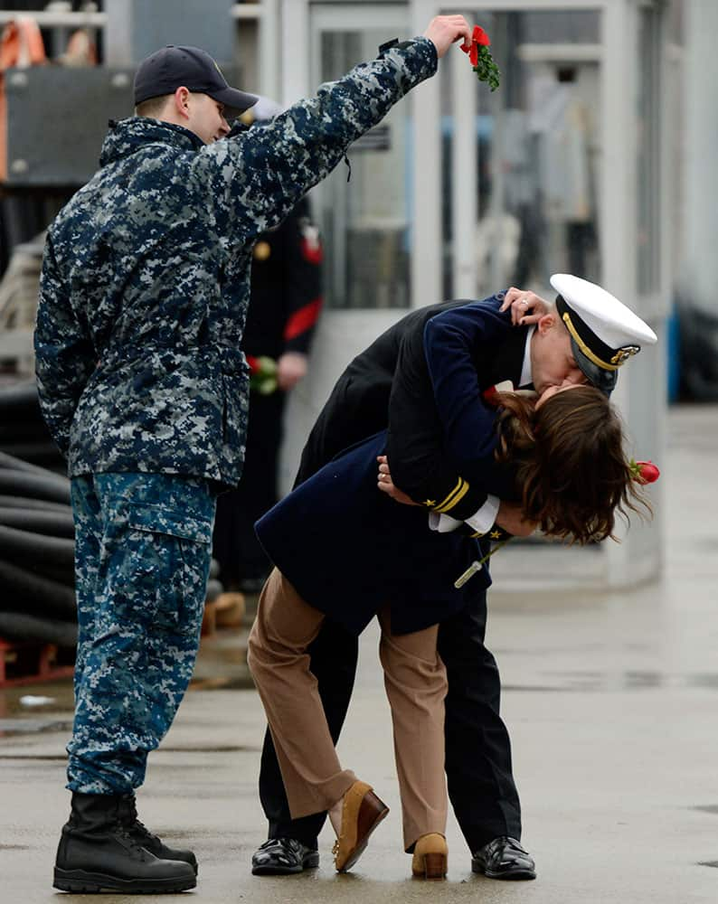 U.S. Navy Lt. jg. Stephen Bogdanowicz, left, holds a sprig of mistletoe as Ensign Morgan Oblinsky and his wife Katie enjoy the ceremonial first kiss as the navy attack submarine USS Hartford returns to the U.S. Navy Submarine Base in Groton, Conn.