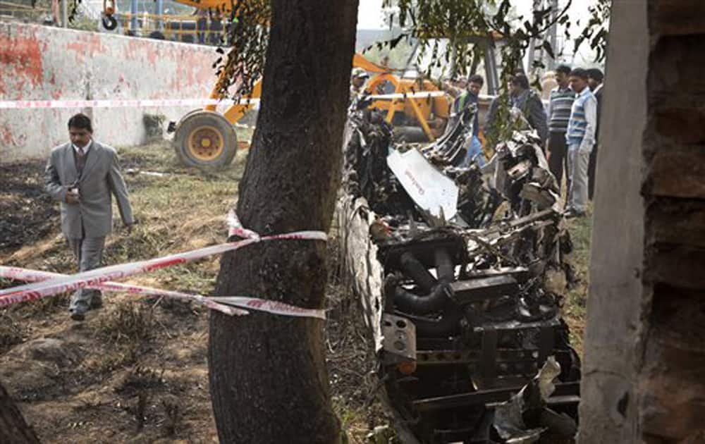 Indian investigators look at the remains of a small Indian paramilitary plane that crashed outside the main airport in New Delhi, Dec 22, 2015. 