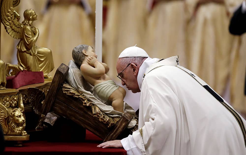 Pope Francis kisses a statue of Baby Jesus as he celebrates the Christmas Eve Mass in St. Peter's Basilica at the Vatican.