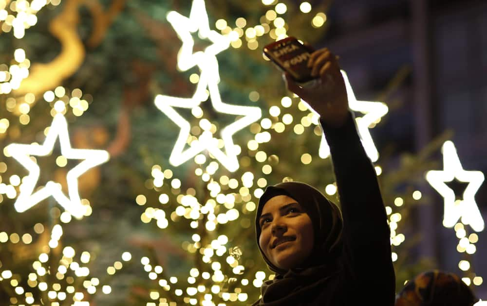 A Muslim Lebanese woman takes a selfie with Christmas trees in Downtown Beirut, Lebanon. 