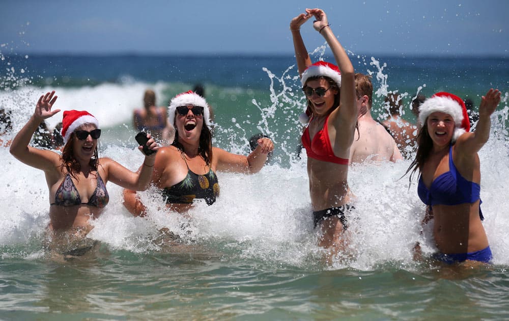 Marlies Noordeloos of the Netherlands, left, Lisa Van De Velde of Belgium, second left, Charlotte Trotter of Britain, second right, and Viktoria Sardarian of Lithuania wear Santa hats while in the surf at Bondi Beach celebrating Christmas Day in Sydney, Australia.
